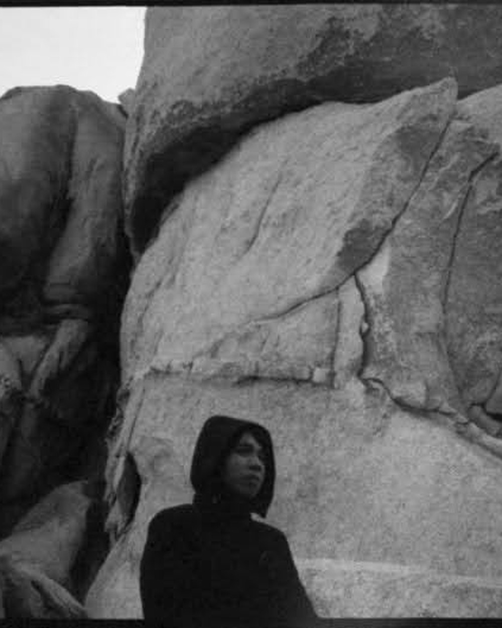 John, hooded, standing small against desert rock formations